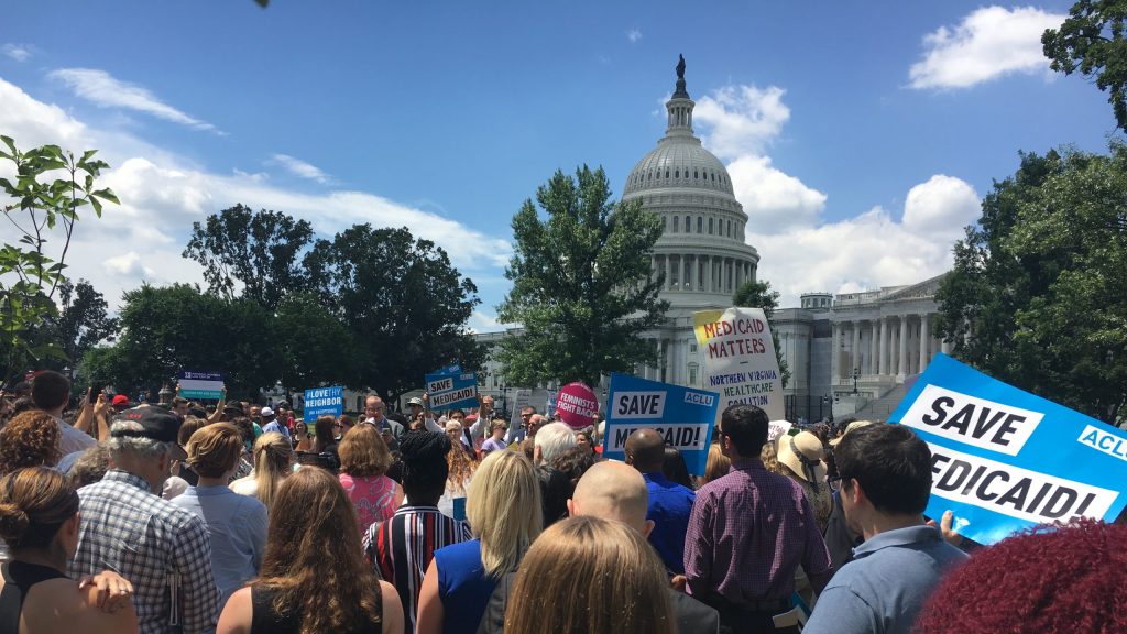 Photo of protesters in front of a Capitol building holding signs that read "SAVE MEDICAID"