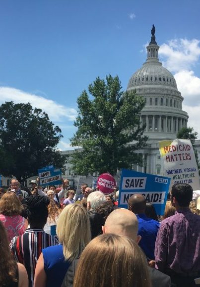 Photo of protesters in front of a Capitol building holding signs that read "SAVE MEDICAID"